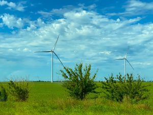 wind turbines on green grass field under blue and white cloudy sky during daytime